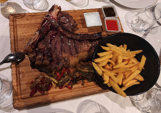 Grilled chuletón steak on a board with fries