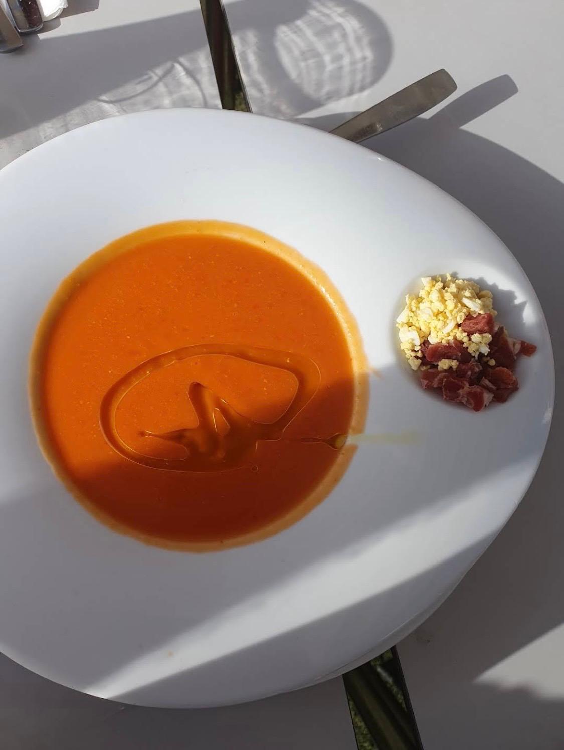 Bowl of salmorejo topped with egg and jamón